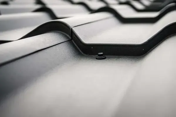 Close up of a metallic roofing surface showcasing wavy tiles and a black screw
