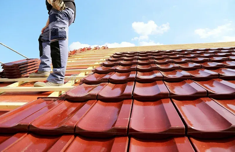 Cherry Hill Person standing on a roof installing red tiles