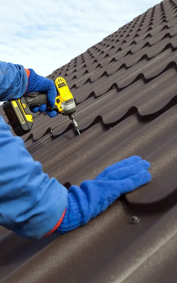 Cherry Hill Person using a drill on a brown metal roof