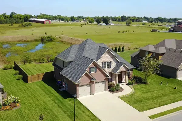 Two-story house with manicured lawn and surrounding fields