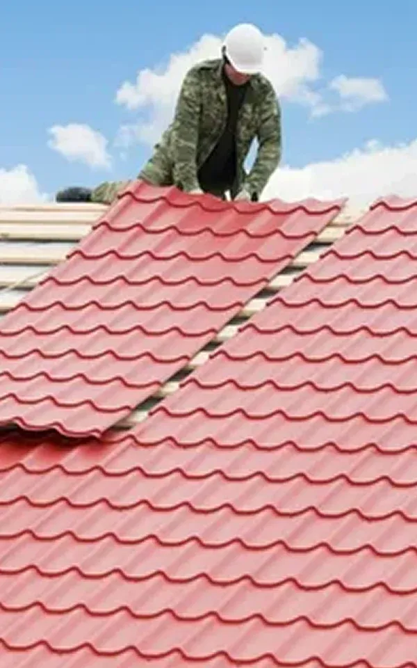 Burlington Worker installing red tiled roofing under blue sky