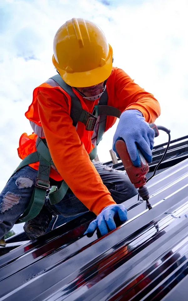 Livingston Worker using a drill on a roof. Safety gear worn