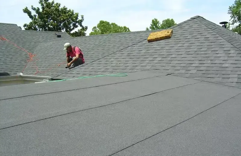 A worker in a pink shirt installs shingles