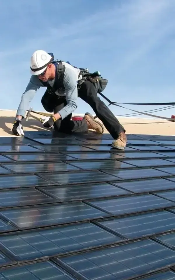 A worker installs solar panels on a sloped roof
