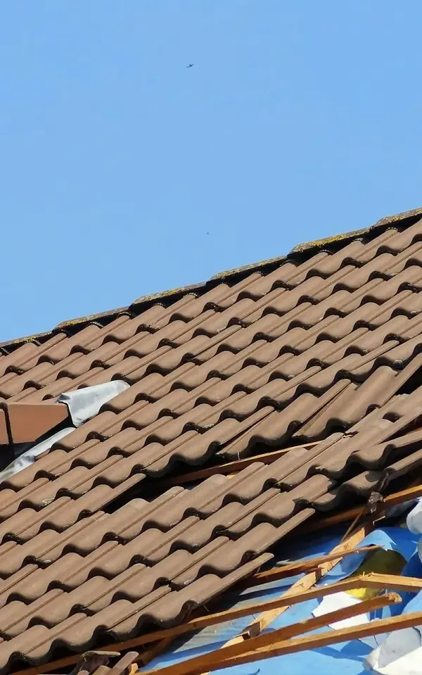 Clifton Damaged brown tile roof against clear blue sky