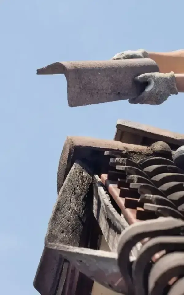 Warren Hand holding a roof tile against blue sky