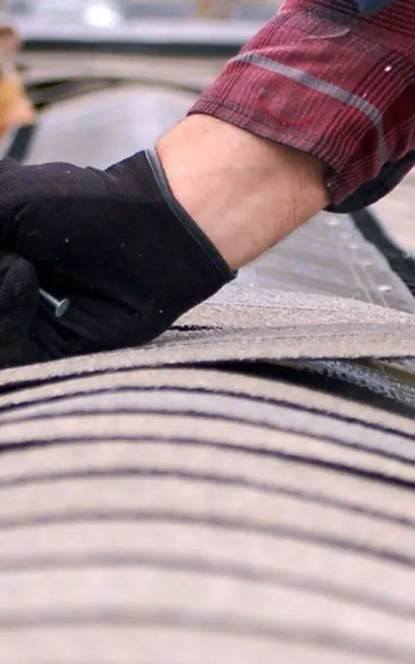 Hand wearing a glove works on roof surface