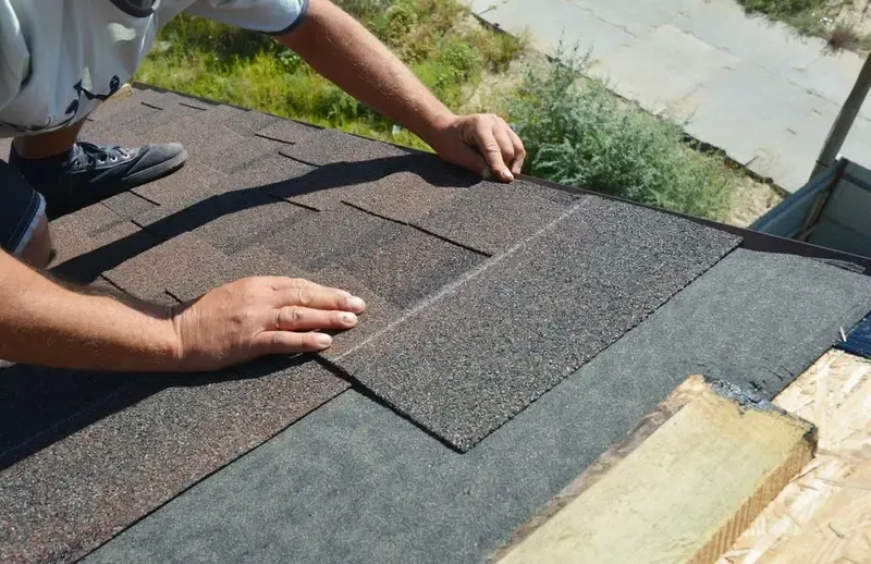 Person installing shingles on a sloped roof