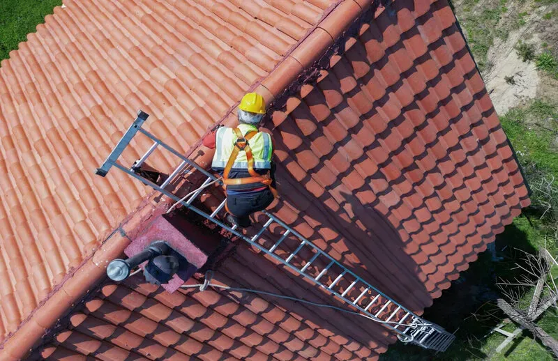 cliffside park Person on ladder repairing a sloped tiled roof