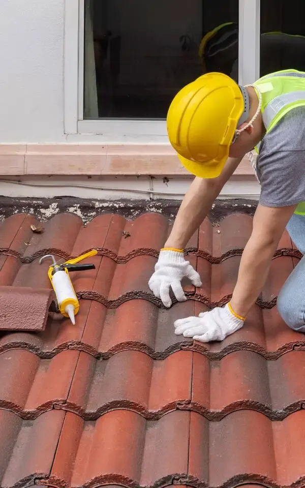 Knowlton Person working on a red tiled roof with gloves