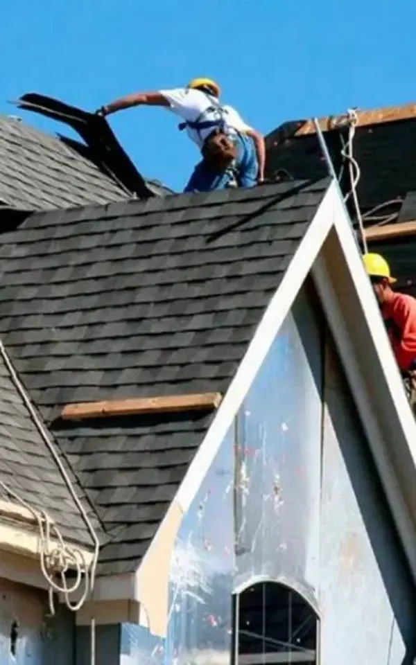 Ridgewood Two roofers, wearing hard hats, work on a sloped roof