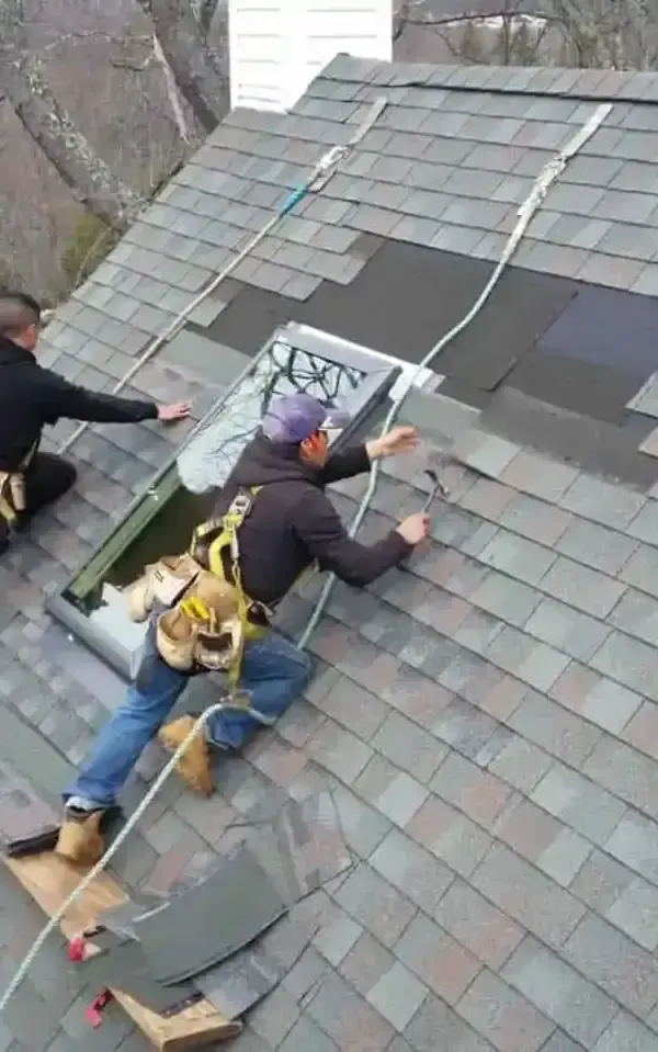 Two workers installing shingles on a sloped roof