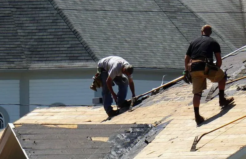 nutley Two workers repairing a roof on a sunny day