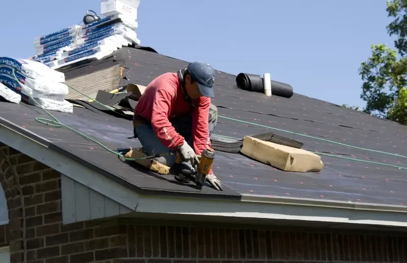 Worker installing roofing material on a house
