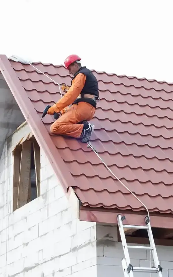 Worker on sloped roof applying material with a tool