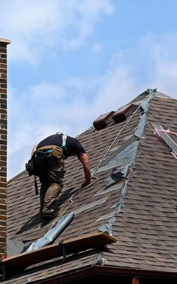 cliffside park Worker repairing a sloped roof under blue sky